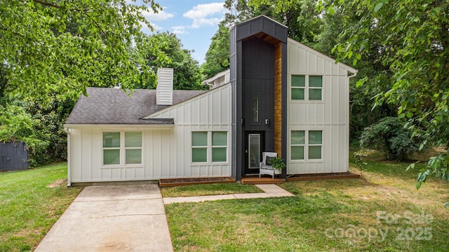 6824 Cortez Trl, Charlotte, NC 28227 - view of front facade with board and batten siding, a chimney, a shingled roof, and a front yard