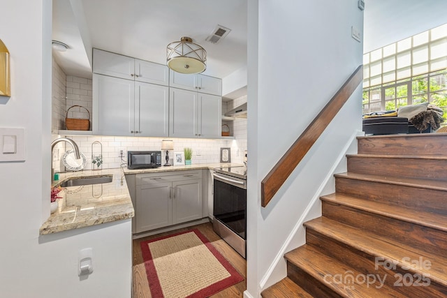 415 W 7th St Unit F, Charlotte, NC 28202 - kitchen featuring a sink, electric stove, black microwave, tasteful backsplash, and light stone counters