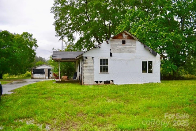 view of front of home featuring a detached carport, a front yard, and driveway