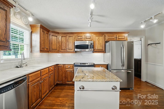1295 Patterson St, China Grove, NC 28023 - kitchen with track lighting, appliances with stainless steel finishes, a textured ceiling, a sink, and dark wood-style flooring