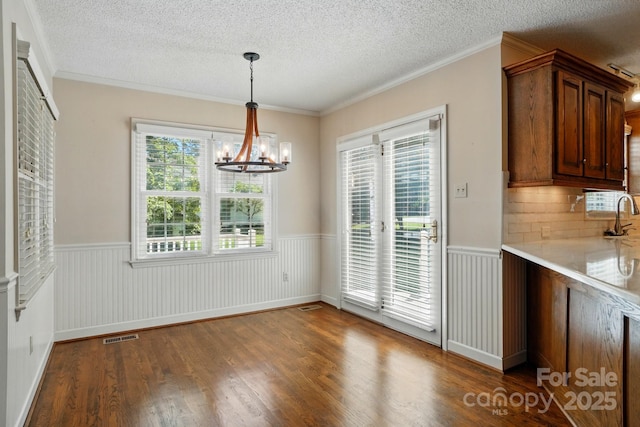 1295 Patterson St, China Grove, NC 28023 - unfurnished dining area featuring wainscoting, a chandelier, wood finished floors, a textured ceiling, and a sink
