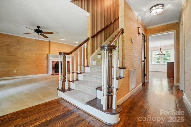 1295 Patterson St, China Grove, NC 28023 - stairway with baseboards, ornamental molding, a ceiling fan, a fireplace, and wood finished floors