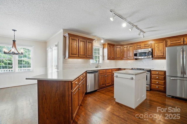 1295 Patterson St, China Grove, NC 28023 - kitchen featuring appliances with stainless steel finishes, a textured ceiling, brown cabinets, dark wood-style floors, and light countertops