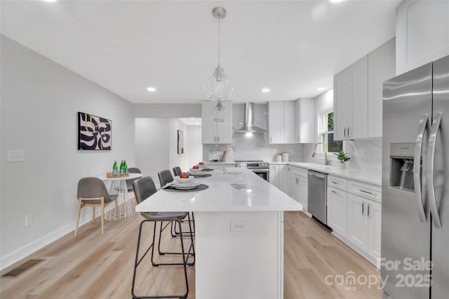 1829 Jennings St, Charlotte, NC 28216 - kitchen with appliances with stainless steel finishes, wall chimney range hood, backsplash, a kitchen bar, and light countertops