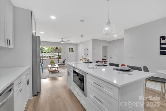 1829 Jennings St, Charlotte, NC 28216 - kitchen featuring appliances with stainless steel finishes, light wood finished floors, light countertops, a kitchen island, and white cabinets
