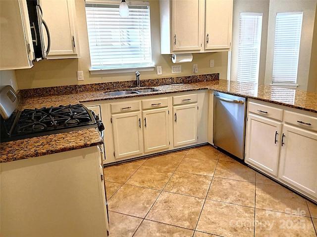 12304 Sandringham Pl, Charlotte, NC 28262 - kitchen with stainless steel appliances, a sink, light tile patterned floors, white cabinetry, and dark stone counters