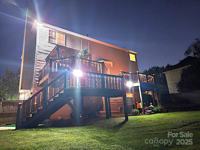 12304 Sandringham Pl, Charlotte, NC 28262 - back of house at night featuring a wooden deck, stairway, and a lawn