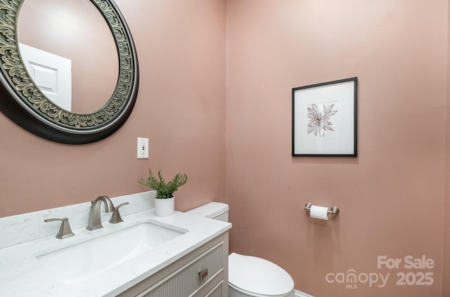 half bathroom featuring toilet, vanity, and baseboards