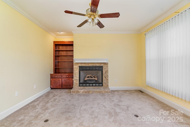 unfurnished living room with ornamental molding, a fireplace with raised hearth, baseboards, carpet flooring, and ceiling fan