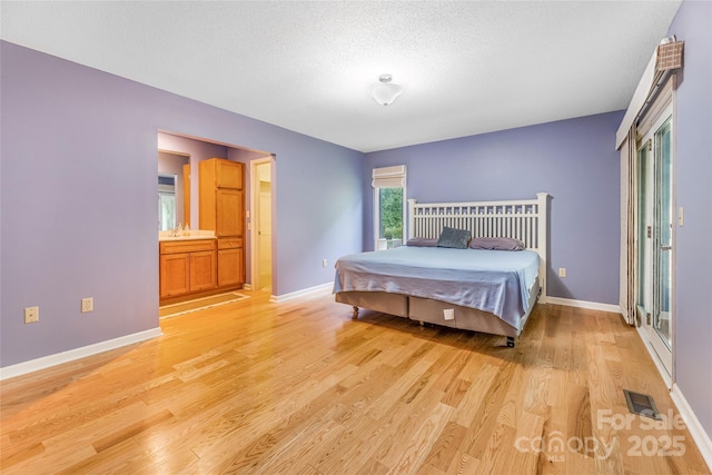 30 Robin Ln, Asheville, NC 28806 - bedroom featuring light wood finished floors, baseboards, a sink, a textured ceiling, and ensuite bathroom