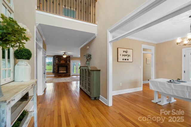 3707 Seagrave Farm Rd, Concord, NC 28025 - foyer entrance featuring ornamental molding, a fireplace, light wood finished floors, baseboards, and a chandelier