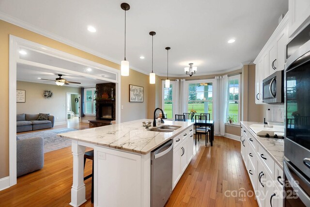 3707 Seagrave Farm Rd, Concord, NC 28025 - kitchen with appliances with stainless steel finishes, crown molding, light wood finished floors, a center island with sink, and white cabinets