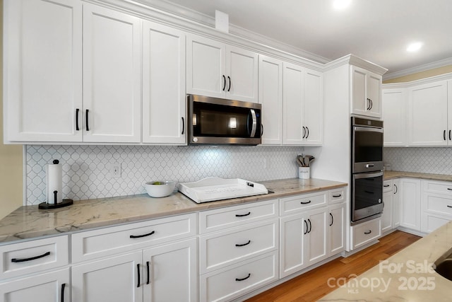3707 Seagrave Farm Rd, Concord, NC 28025 - kitchen with stainless steel appliances, white cabinetry, light wood-style flooring, decorative backsplash, and ornamental molding
