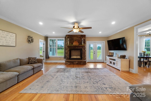 3707 Seagrave Farm Rd, Concord, NC 28025 - living area with ornamental molding, light wood-type flooring, ceiling fan, a stone fireplace, and french doors