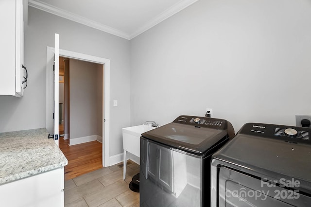 3707 Seagrave Farm Rd, Concord, NC 28025 - clothes washing area featuring washing machine and clothes dryer, cabinet space, crown molding, baseboards, and light wood-style floors