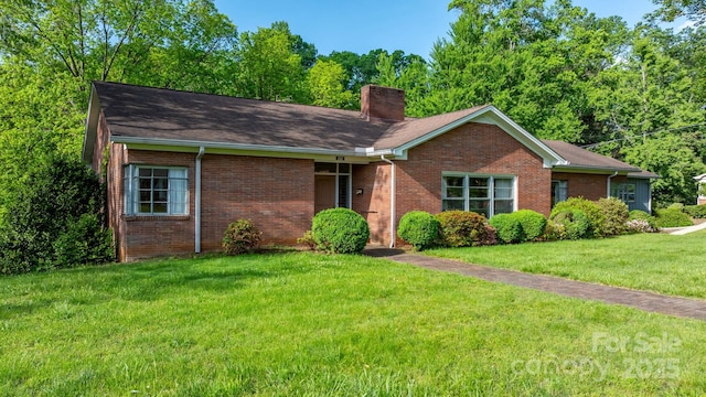 ranch-style home with a chimney, brick siding, a front lawn, and roof with shingles