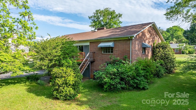 back of house featuring a lawn, brick siding, and a deck