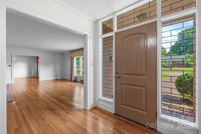 entryway with wood finished floors, baseboards, and ornamental molding