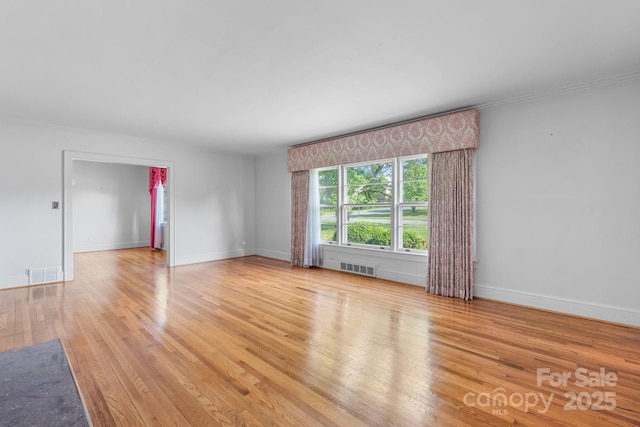 empty room featuring light wood-style floors, baseboards, and ornamental molding