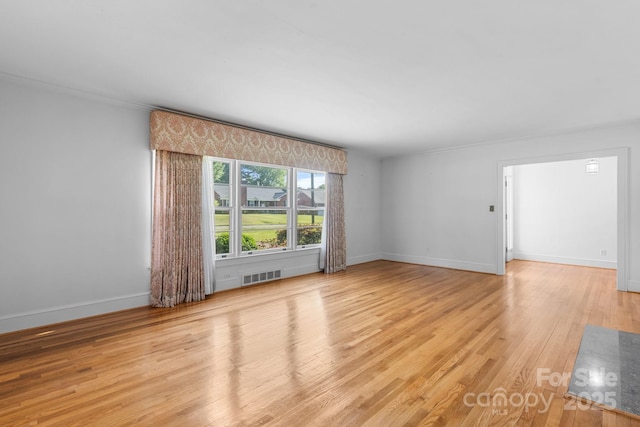 unfurnished room with wood finished floors, baseboards, and ornamental molding