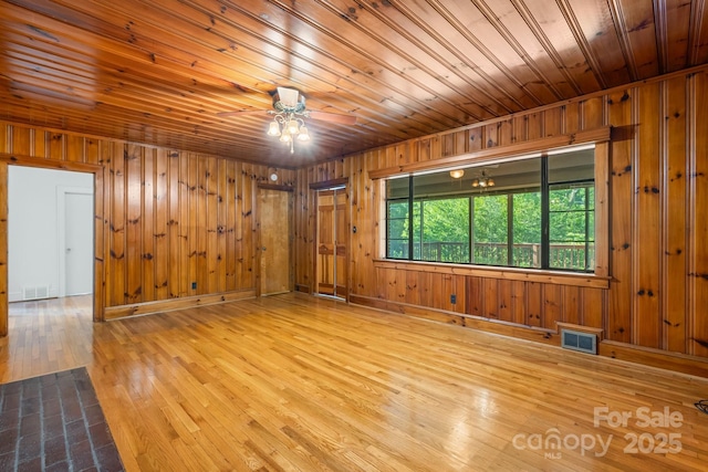 unfurnished room featuring wood-type flooring, wooden walls, ceiling fan, and wooden ceiling