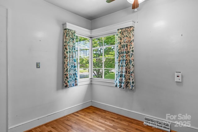 spare room with baseboards, light wood-type flooring, and a ceiling fan