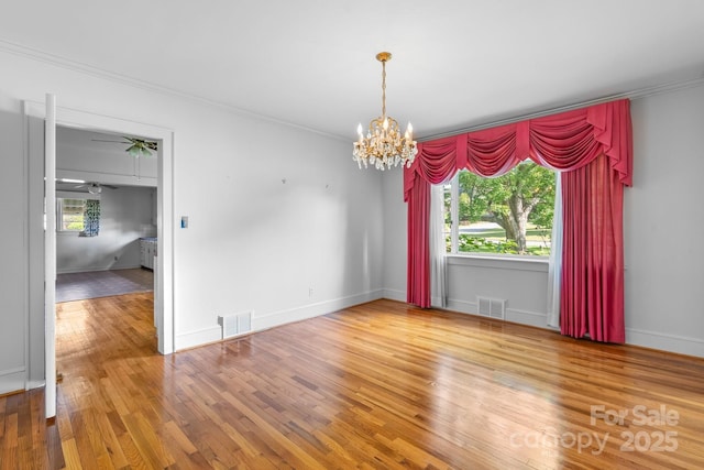 unfurnished dining area with a chandelier, crown molding, wood finished floors, baseboards, and ceiling fan