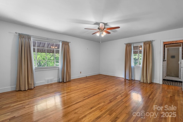 empty room with wood finished floors, a ceiling fan, and baseboards