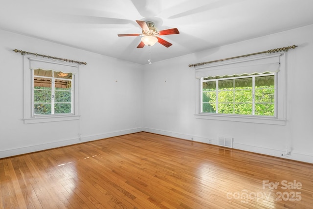 spare room with plenty of natural light, light wood-style flooring, a ceiling fan, and baseboards