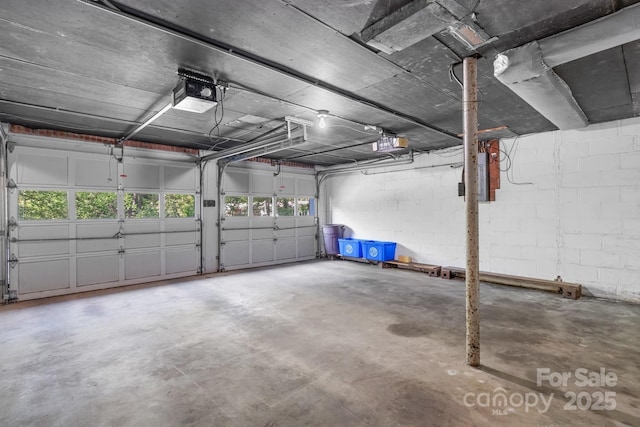 garage with a garage door opener and concrete block wall