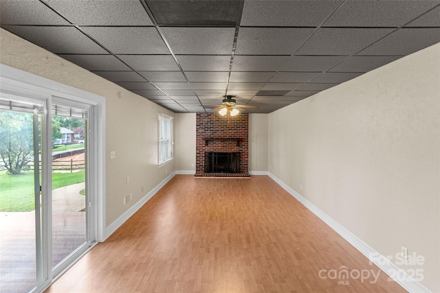 8024 Bradford Ln, Denver, NC 28037 - unfurnished living room featuring light wood-type flooring, a drop ceiling, a ceiling fan, a fireplace, and baseboards