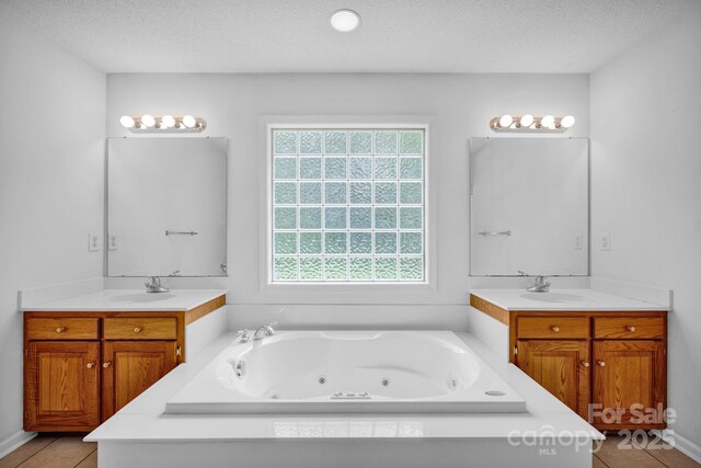 5678 Cedar Run Dr, Denver, NC 28037 - bathroom featuring healthy amount of natural light, a textured ceiling, a tub with jets, and two vanities