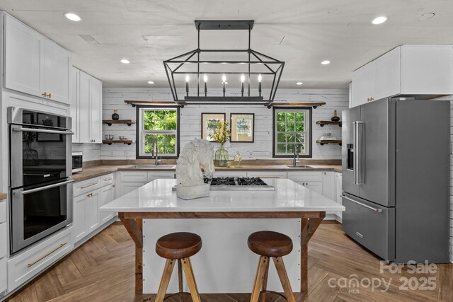 5229 Mt Holly Huntersville Rd, Charlotte, NC 28216 - kitchen featuring appliances with stainless steel finishes, open shelves, a sink, a kitchen bar, and healthy amount of natural light