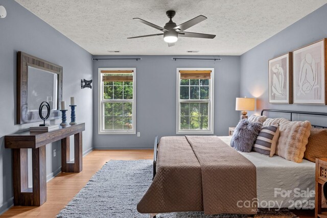 5229 Mt Holly Huntersville Rd, Charlotte, NC 28216 - bedroom featuring light wood-style floors, a textured ceiling, a ceiling fan, and baseboards