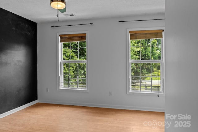 5229 Mt Holly Huntersville Rd, Charlotte, NC 28216 - empty room featuring light wood-style floors, plenty of natural light, baseboards, and a textured ceiling