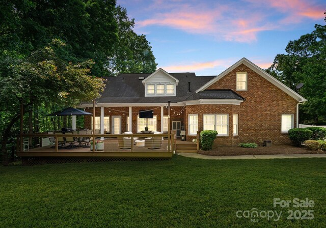 328 Whippoorwill Rd, Mooresville, NC 28117 - back of property at dusk featuring brick siding, a wooden deck, and a lawn