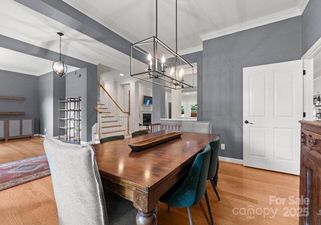 328 Whippoorwill Rd, Mooresville, NC 28117 - dining room with light wood finished floors, stairs, ornamental molding, a chandelier, and baseboards