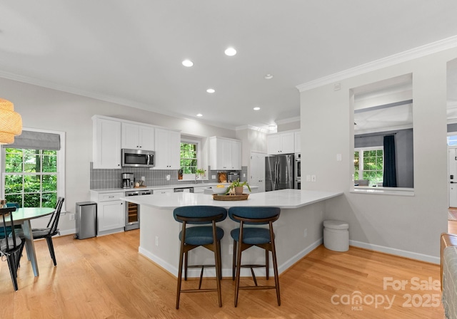 328 Whippoorwill Rd, Mooresville, NC 28117 - kitchen with stainless steel appliances, ornamental molding, beverage cooler, light countertops, and white cabinets