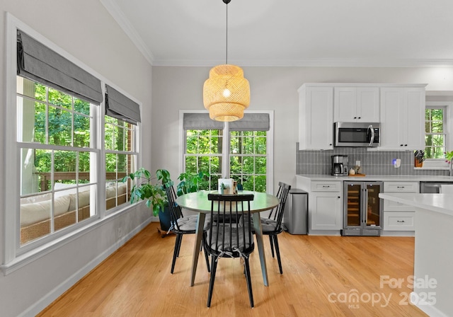 328 Whippoorwill Rd, Mooresville, NC 28117 - dining room with beverage cooler, crown molding, light wood-style floors, and baseboards