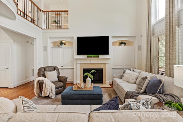 7507 Meadowgate Ln, Waxhaw, NC 28173 - living room with a towering ceiling, wood finished floors, built in shelves, a fireplace, and baseboards