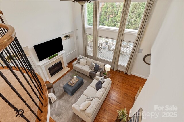 7507 Meadowgate Ln, Waxhaw, NC 28173 - living room with a towering ceiling, wood finished floors, baseboards, a fireplace with flush hearth, and stairway