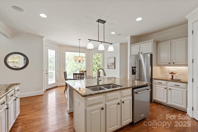 7507 Meadowgate Ln, Waxhaw, NC 28173 - kitchen featuring a chandelier, a sink, appliances with stainless steel finishes, wood finished floors, and ornamental molding