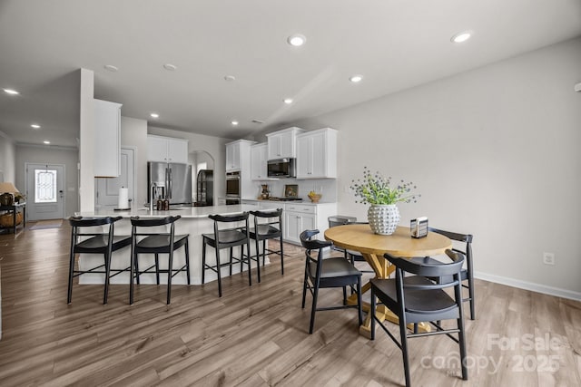 dining space with light wood-style flooring, recessed lighting, and baseboards