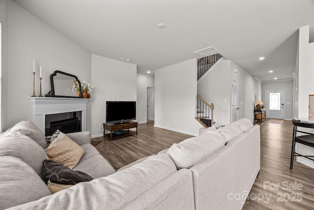 living area featuring stairway, wood finished floors, a fireplace, recessed lighting, and baseboards