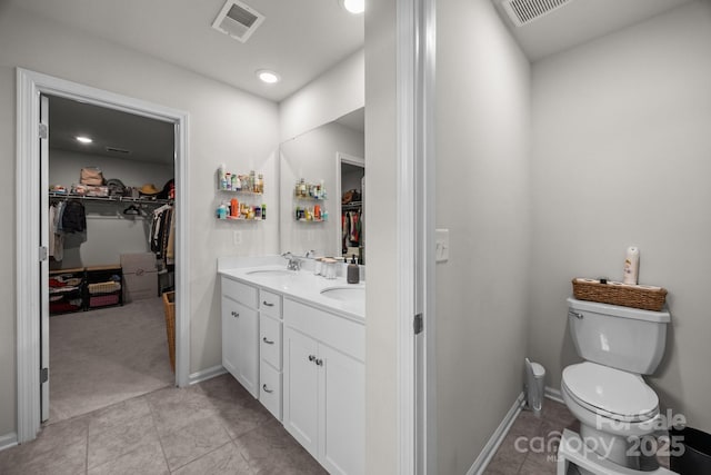full bathroom with toilet, a walk in closet, double vanity, tile patterned flooring, and baseboards