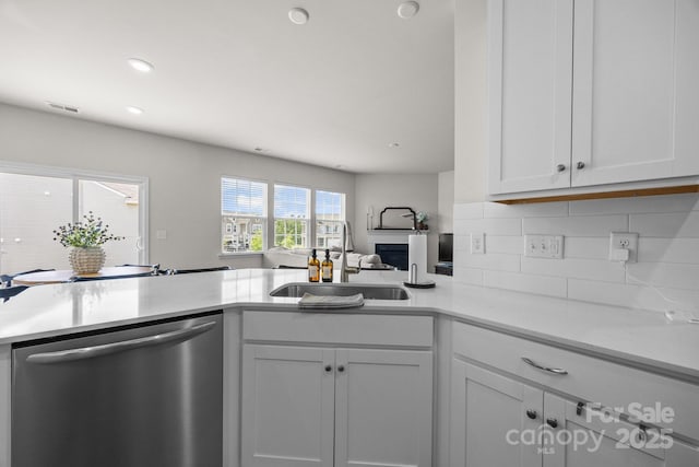 kitchen with stainless steel dishwasher, a sink, light countertops, decorative backsplash, and open floor plan