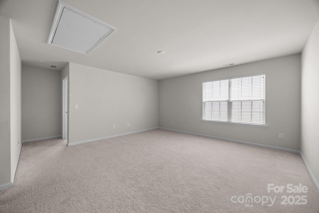 unfurnished room with attic access, carpet flooring, and baseboards