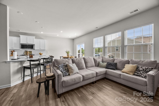 living room with wood finished floors, recessed lighting, and baseboards