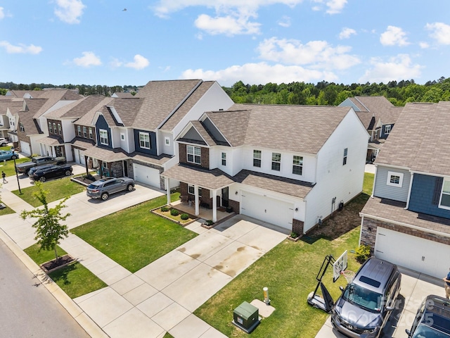 view of front of home featuring a residential view, driveway, an attached garage, a shingled roof, and a front yard