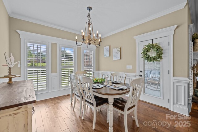 335 Wintergreen Ct, Kings Mountain, NC 28086 - dining area with a chandelier, wood finished floors, a wainscoted wall, ornamental molding, and a decorative wall
